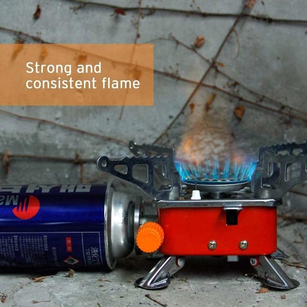 Portable gas stove with a canister and visible flame on a concrete surface.