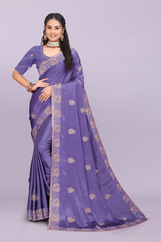 Woman wearing a purple saree with gold patterns on a light purple background