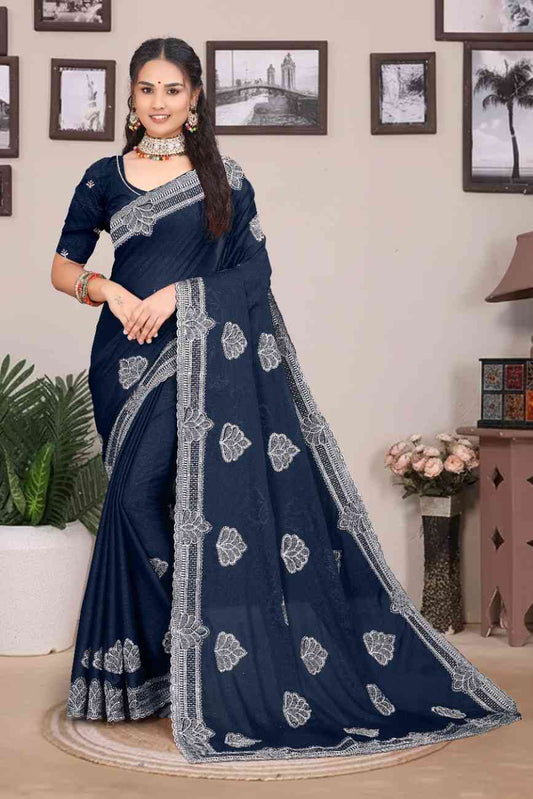 Woman wearing a navy blue saree with white patterns in a room setting.