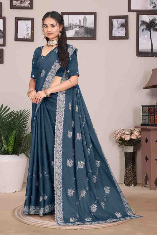 Woman wearing a blue saree with a white border in a room setting.