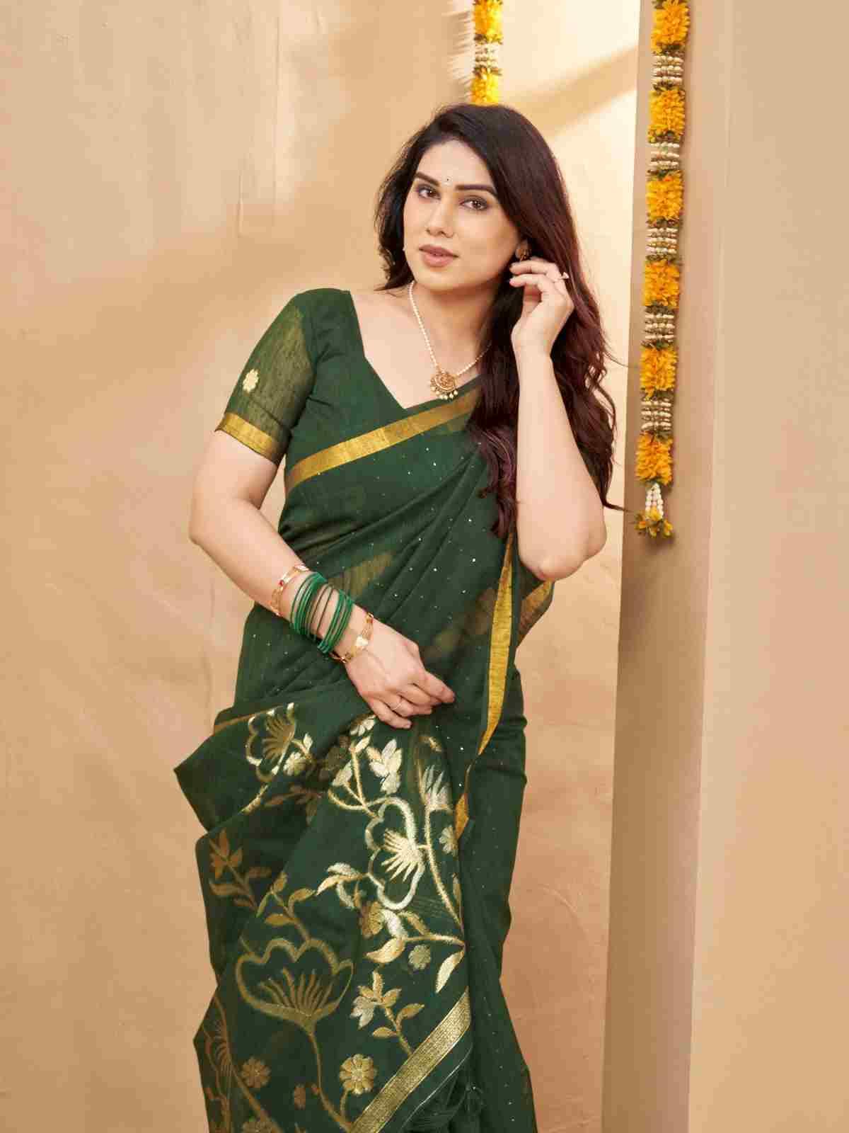 Close-up pose of woman in green linen silk saree with gold floral pallu.