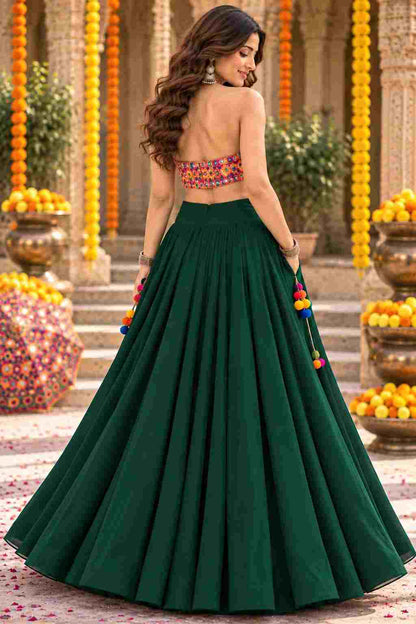 Backless view of dark green georgette lehenga choli with pom-pom accents.   