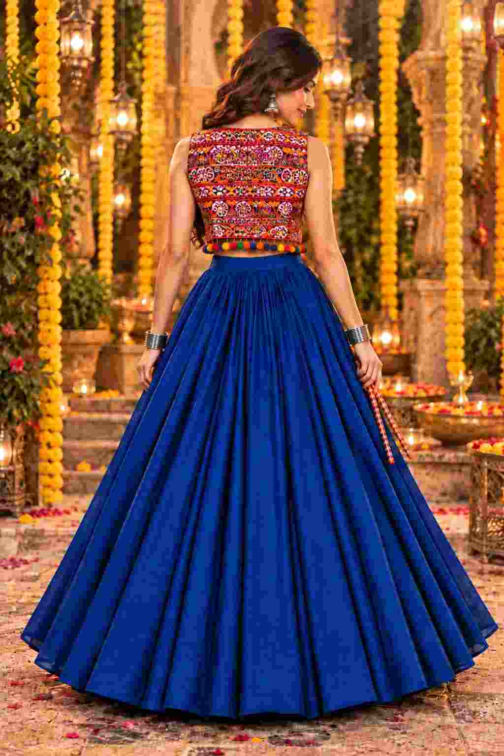 Back view of a royal blue lehenga showcasing a colorful embroidered jacket.   