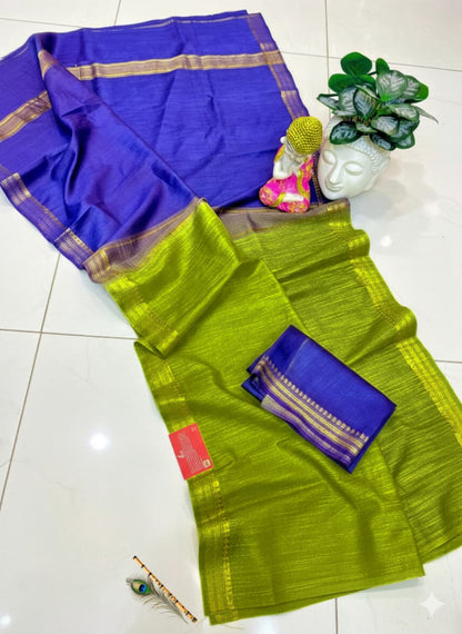 Two sarees, one blue and one green, on a white surface with a small plant and measuring stick.
