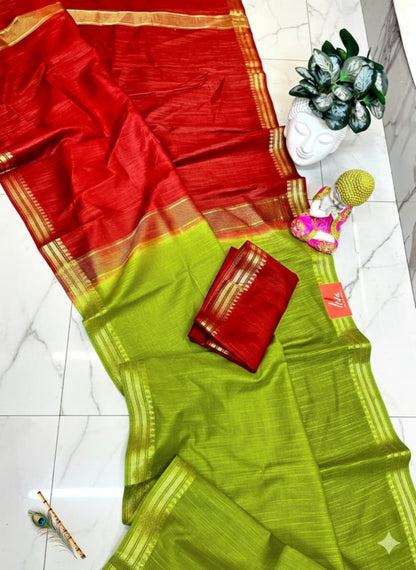 Red and green saree with a small statue and decorative items on a white floor.