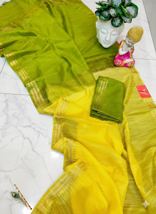 Yellow saree with green border on a white floor with decorative items.