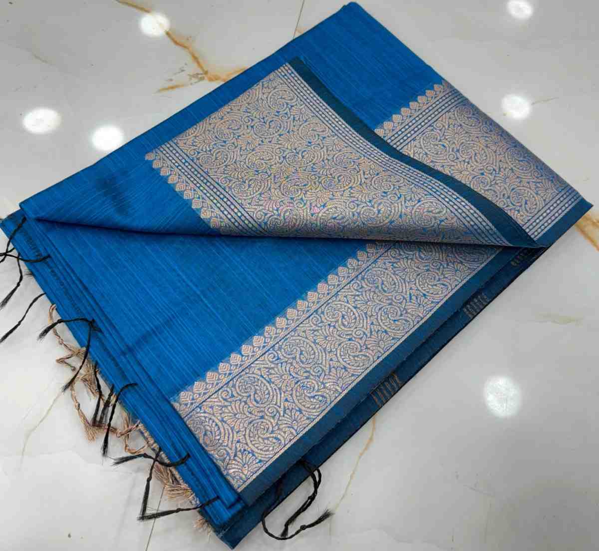 Blue saree with white border on a marble floor