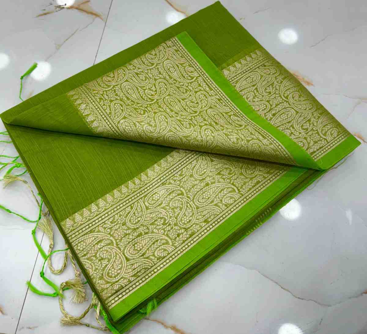 Green fabric with intricate white patterns on a white tiled floor