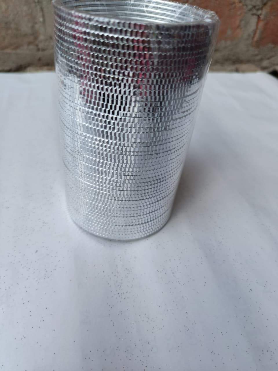 Silver mesh cup on a white surface with a blurred background