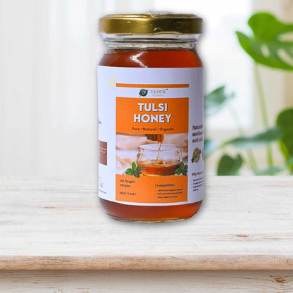 Jar of Tulsi honey on a wooden surface with a blurred plant in the background