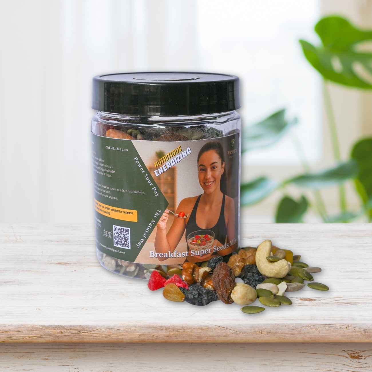 Jar of 'Breakfast Super' mix with a woman on the label, surrounded by various nuts and seeds on a wooden surface.