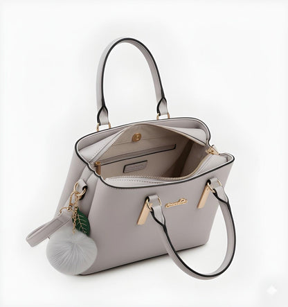 Light gray handbag with a decorative charm on a white background