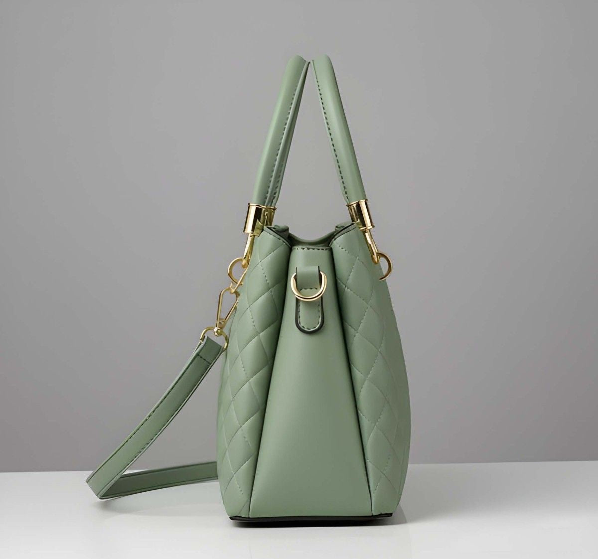 Green handbag with gold accents on a gray background