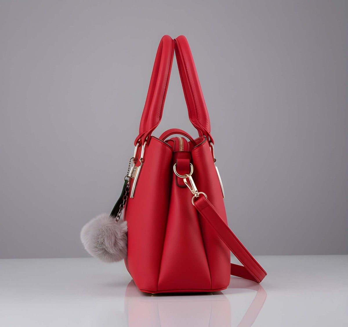 Red handbag with a fluffy pom-pom on a gray background