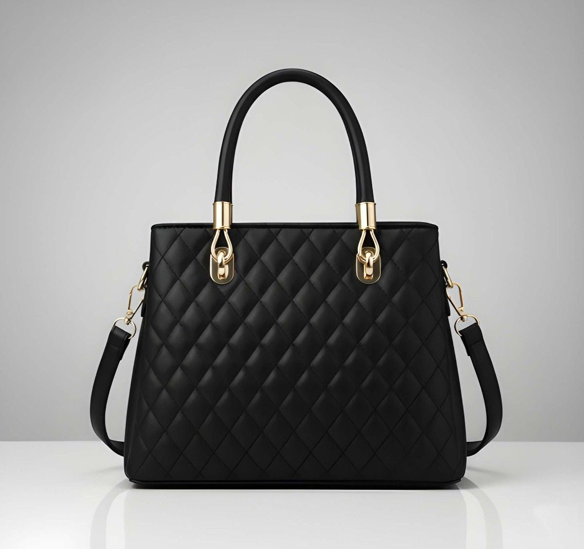 Black quilted handbag with gold accents on a gray background