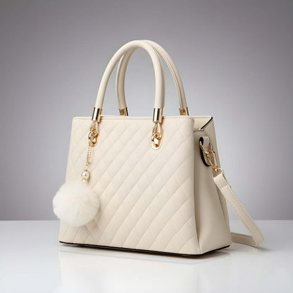 White quilted handbag with gold accents on a gray background