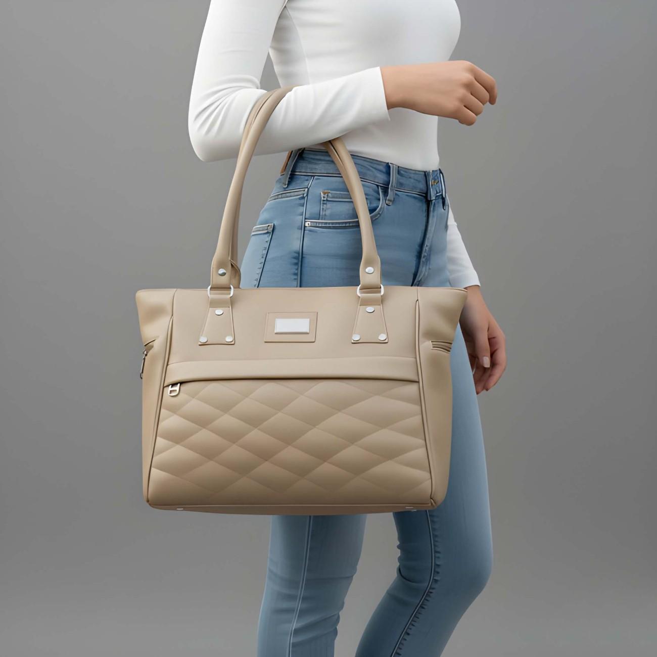 Beige quilted handbag held by a person wearing blue jeans against a gray background
