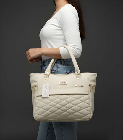 Person holding a beige quilted handbag with a visible brand tag against a dark background
