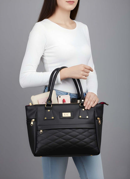 Person holding a black quilted handbag against a gray background