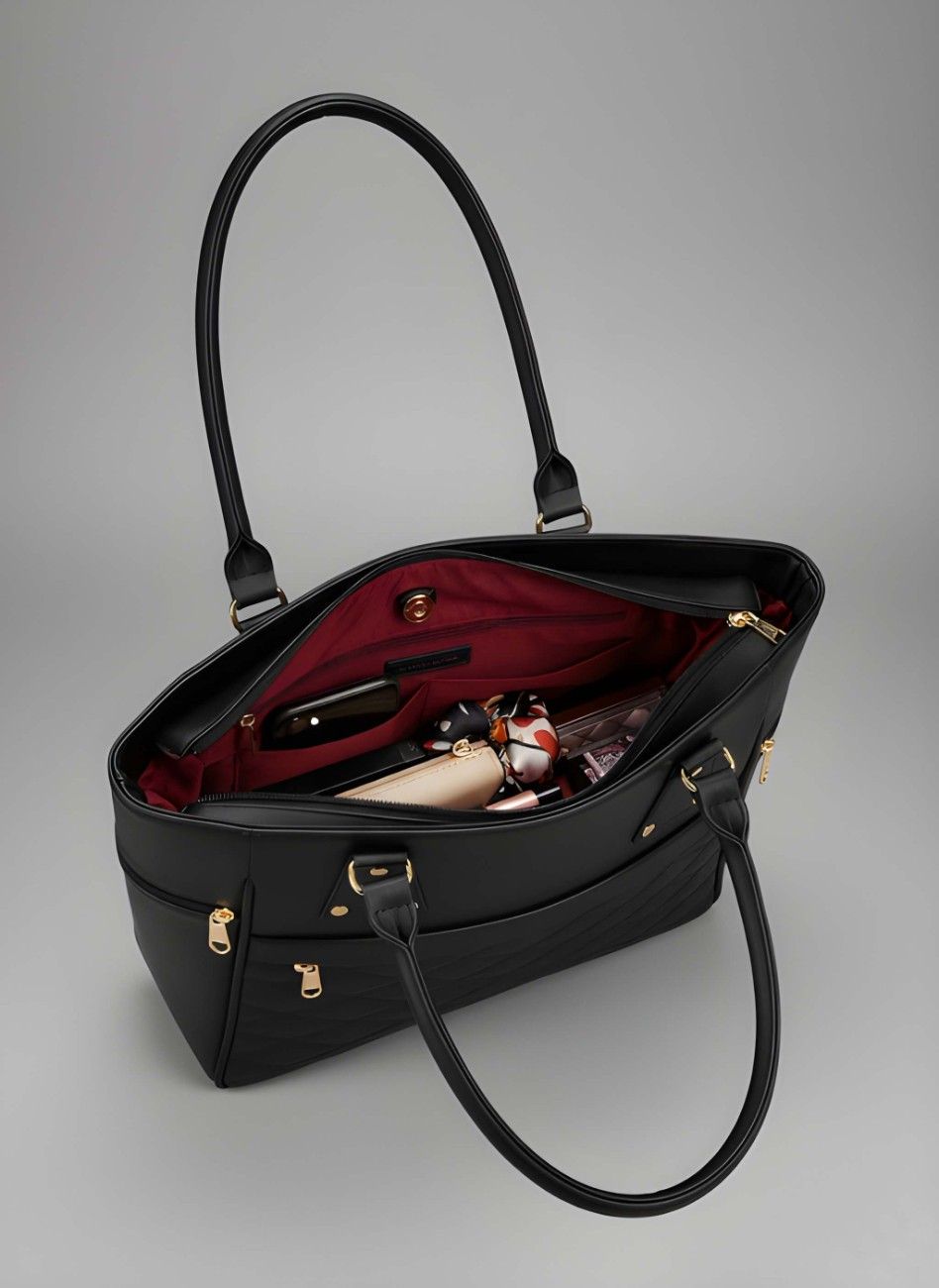 Black handbag with gold accents on a gray background