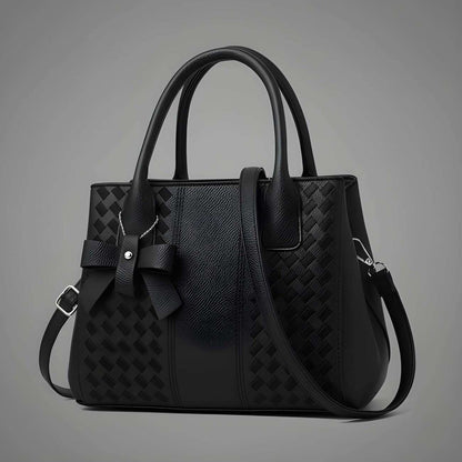 Black handbag with a textured pattern on a gray background