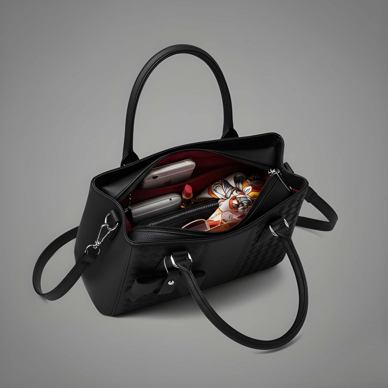 Black handbag with makeup items on a gray background