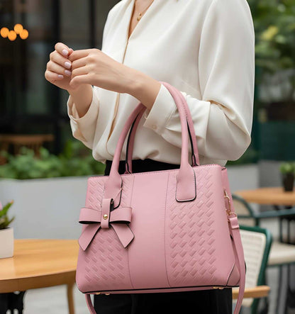 Person holding a pink handbag with a bow detail in an outdoor setting