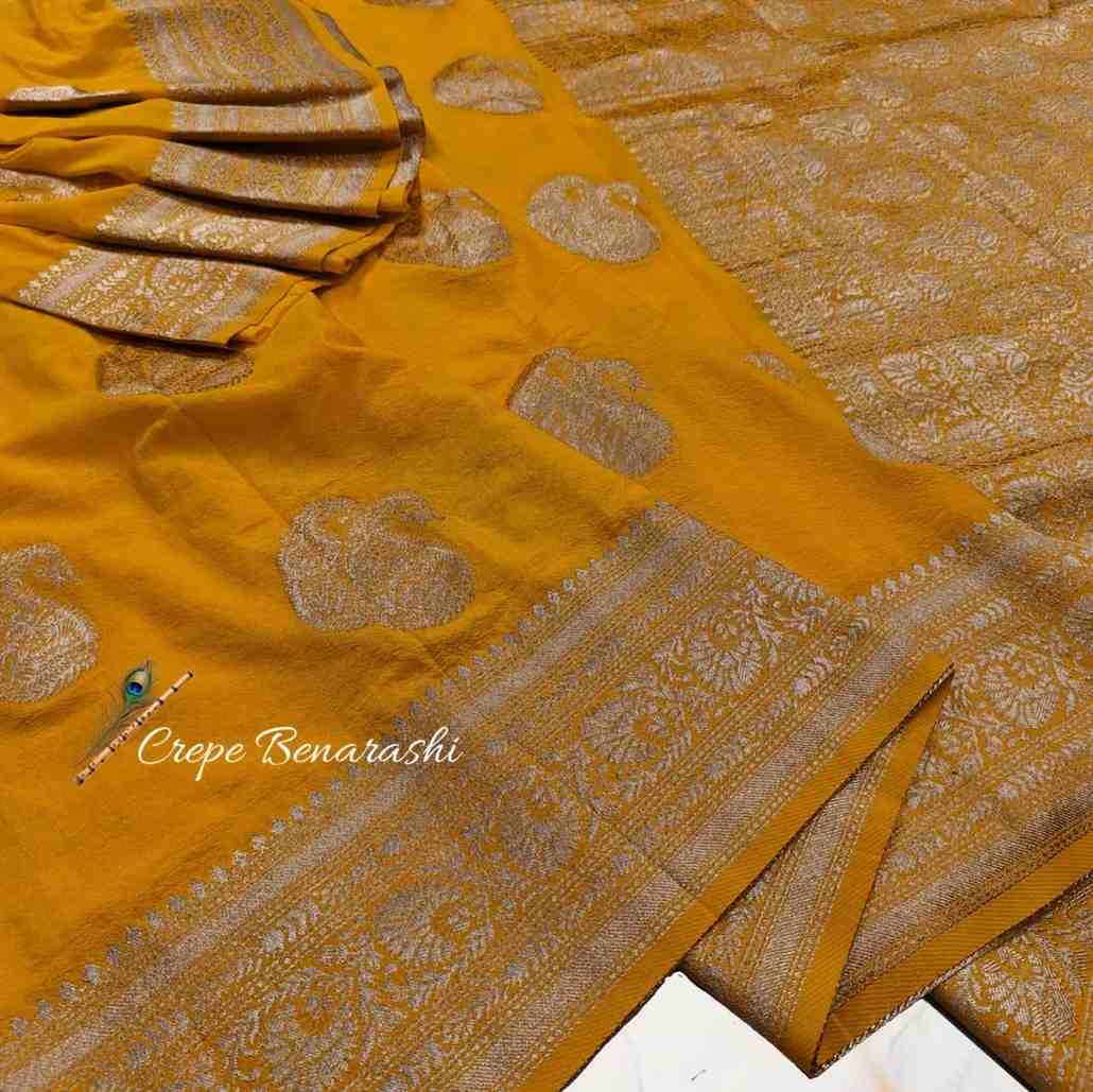 Mustard yellow saree with intricate patterns and a brand name on a white background