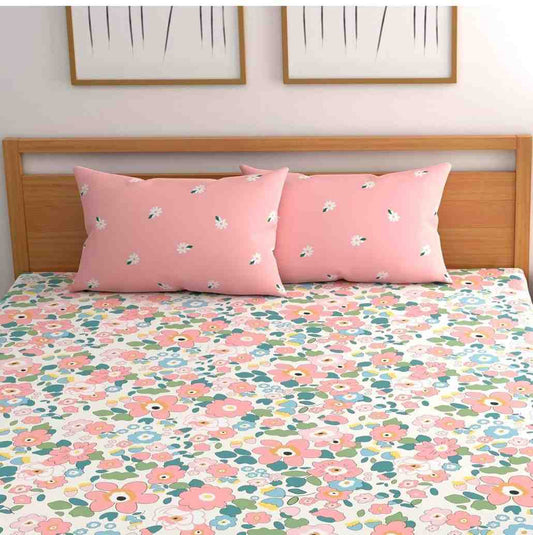 Floral bedspread with matching pillows on a bed with wooden headboard.