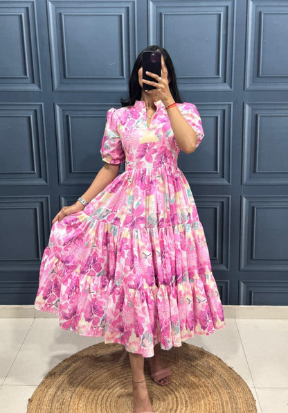 Person wearing a pink floral dress against a blue paneled wall.