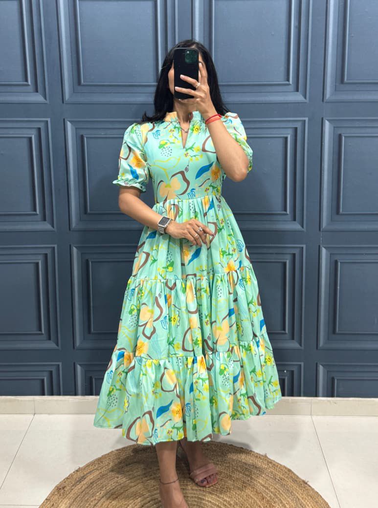 Person wearing a green floral dress taking a mirror selfie against a blue paneled wall.