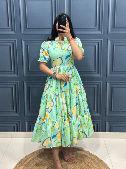 Person wearing a green floral dress taking a mirror selfie against a blue paneled wall.