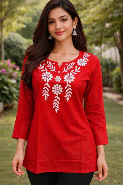 Woman wearing a red embroidered top outdoors