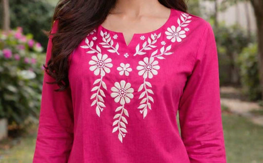 Pink top with white floral patterns worn by a person outdoors.